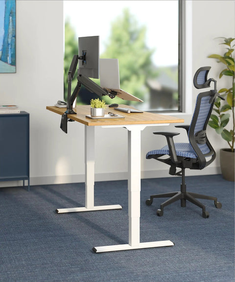Sturdy Bamboo Standing Desk With 3 Stage Dual Motor Lift For A Smooth Easy Sit Stand Transition 55 By 28 Inch Desk 220 Lb Capacity Memory Presets Solid Bamboo Top And White Frame Electric Adjustable Height Ships In Two Boxes in a bright office setting.