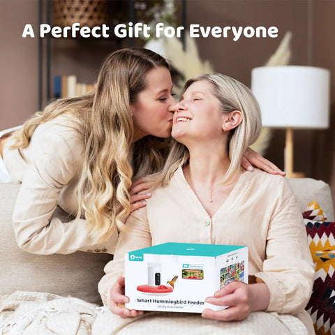 Two people sitting on a couch holding a box of Smart Hummingbird Feeder With Camera And Solar Power, Live View And 1080P Video.
