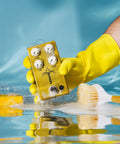 Person holds Morning Glory Clean Overdrive Pedal With Transparent Tone, Clear Pick Attack in yellow glove above reflective surface.
