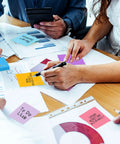 Group using Burst Of Color Sticky Notes Refills 3x3 Pop Up Pads With 9 Bright Colors, arranging notes on desk with graphs
