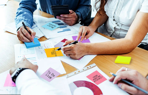 Group using Burst Of Color Sticky Notes Refills 3x3 Pop Up Pads With 9 Bright Colors, arranging notes on desk with graphs
