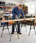 Man using Badass 2 Pack Folding Sawhorse 660 Lb Heavy Duty Metal Work Stands to cut lumber in a workshop.