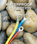 Heat-shrink wire terminals; three insulated ring terminals in yellow, blue, and orange on wet pebbles.