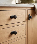 Matte Black Cabinet Knobs With Scalloped Backplates 6 Pack Featuring Slick Fluted Floral Handles on wooden kitchen drawers.