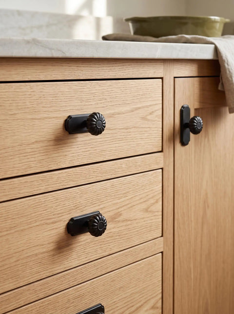 Matte Black Cabinet Knobs With Scalloped Backplates 6 Pack Featuring Slick Fluted Floral Handles on wooden kitchen drawers.