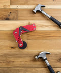 Thinking Process: red aluminum motorcycle chain adjuster with roller and two hammers on wooden floor