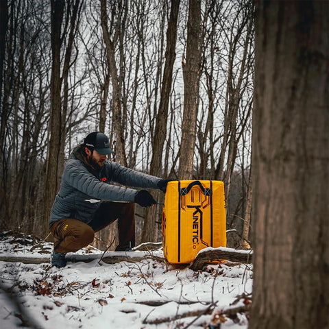 Man with Yellow Jacket Kinetic One Point Zero 65 Pound Portable Field Point Archery Target Bag in snowy forest