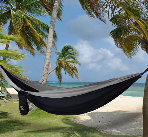 Ultra Comfortable Extra Large Double Camping Hammock With Tree Straps For Outdoor And Indoor Use Portable Gear For Two Supports Up To 500 Lbs 125 In By 79 In Hammock Bed Black And Gray hanging between palm trees on a beach
