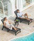 Weather Resistant HDPE Outdoor Side Table With Real Wood Grain Look For Small Patios Porch And Balcony Heavy Duty 200 Lb Capacity Poolside Ready Easy Maintenance Black next to loungers by pool.