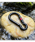 Heavy Duty Carabiner Clip With Spring Snap Wire Gate 3 Inch Aluminum Karabiner resting on a wet rock in a stream