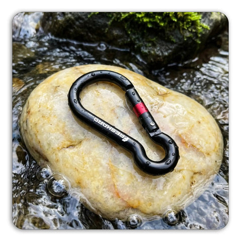 Heavy Duty Carabiner Clip With Spring Snap Wire Gate 3 Inch Aluminum Karabiner resting on a wet rock in a stream