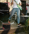 Musician playing guitar with Portable 15W Guitar Amp With Bluetooth Built In Looper And Drum Machine outdoors by stage