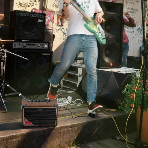 Musician playing guitar with Portable 15W Guitar Amp With Bluetooth Built In Looper And Drum Machine outdoors by stage
