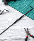 Badass Double Pointed Scriber Tool 10 Inch Long With Slick Textured Grip on cutting mat with tools, ideal for precise marking.