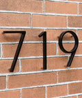Set of three 5-inch black stainless steel floating house numbers 7, 1, 9 with nail kit on brick wall