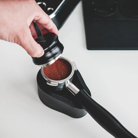 Hand using 51mm Espresso Coffee Distribution Tool With Adjustable Depth For Even Tamp And Consistent Extraction Leveling Coffee Leveler Fits Delonghi 51mm Portafilter Stainless Steel Base Barista Accessory over portafilter with coffee grounds