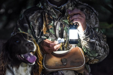 Hunter with dog using Siege X Rechargeable Lantern Flashlight 360 Degree Light 300 Lumen Output in a forest setting at night.