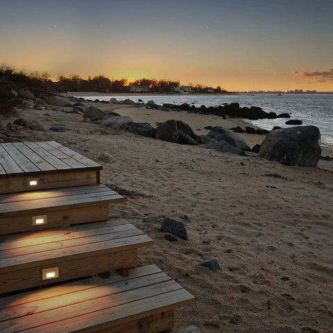 Beachside stairs illuminated by Ledme 120V Horizontal Indoor Outdoor Step And Wall Light With Built In 3000K LED White Finish Energy Efficient Landscape Fixture For Stairs Walls And Walkways Easy 2x4 Junction Box Install at sunset.