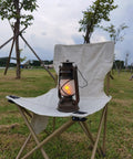 Bronze Outdoor LED Lantern With Vintage Flame Effect on a white folding chair in a garden setting.