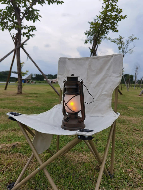 Bronze Outdoor LED Lantern With Vintage Flame Effect on a white folding chair in a garden setting.