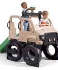 Two toddlers playing on Truck Climber Outdoor Playset For Kids, featuring a slide and climbing wall, in a playroom setting.