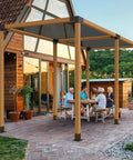 Outdoor pergola with Four Way 4x4 Pergola Brackets Heavy Duty Tough As Nails Corner Brackets For Wood Beams Easy Installation For Outdoor Gazebos Patios Log Cabins 2 Pack Post Base Hardware To Stop Rot And Sun Damage Weatherproof installed on a patio with people gathered underneath.