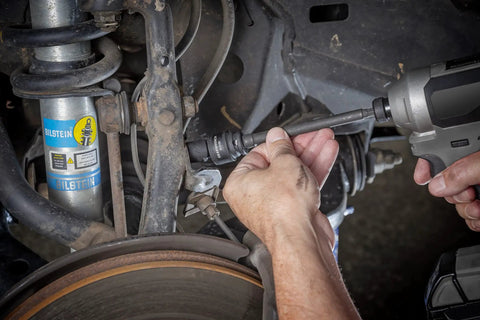 Mechanic using 8 Pc Three Eighths Inch Drive 6 Point Universal Impact Socket Set SAE on car suspension for tough jobs.