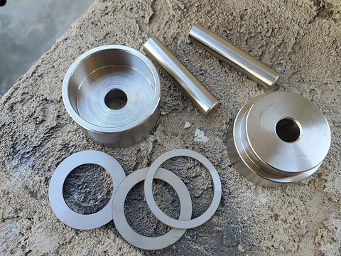 Total Game Changer Coin Ring Punch Set With Four Sleek Self Centering Tools on a workbench with metal circular blanks.