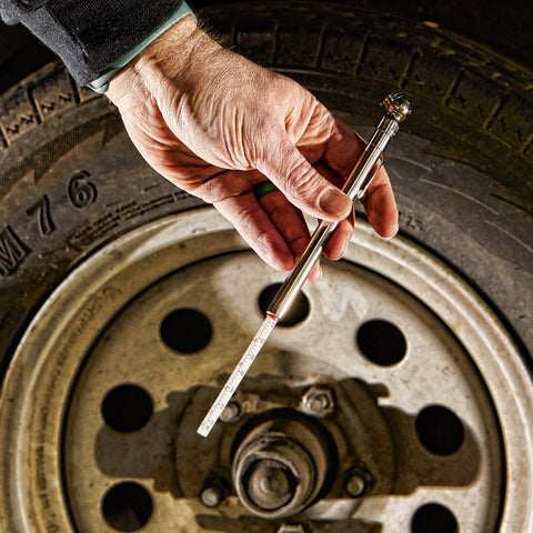 Hand holding High Pressure Car Tire Gauge With Pencil Style Tread Depth Meter Built In Deflator Valve One Sixteenth Inch Increments