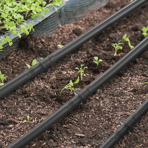 Ultimate 300 Piece Drip Irrigation Fittings Kit For Quarter Inch Tubing installed in garden soil with young plants visible