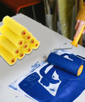 10 Piece Premium Sponge Texture Paint Rollers For Walls And Drywall Easy Replacement Sleeves Fit Standard Frames stacked beside a roller in use.