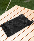 Folded black trampoline shade cover sun shelter for outdoor trampolines weather resistant and rainproof canopy on wooden table.