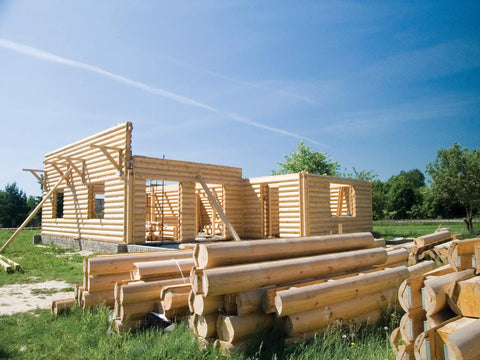 Log cabin under construction with timber logs on ground, strong-drive timber screws used for fastening.