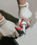 Person using caulking gun while wearing Red Work Gloves Pack Of 300 Touch Screen Ready Latex Palm Coated Nitrile Safety Gloves