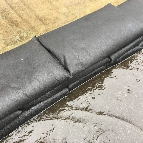 Grab And Go Flood Kit With 20 Water Activated Flood Bags In A Bucket, black barriers absorbing water on pavement