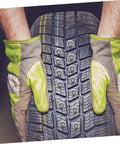 Hands in gloves holding a winter tire fitted with Premium Tungsten Winter Tire Studs Pack for icy road traction.