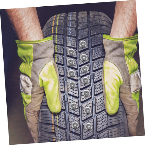 Hands in gloves holding a winter tire fitted with Premium Tungsten Winter Tire Studs Pack for icy road traction.