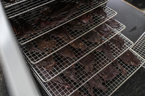 Heavy Duty Food Dehydrator With Digital Thermostat And Set It Forget It Timer Six Grease Resistant Stainless Steel Trays holding jerky.