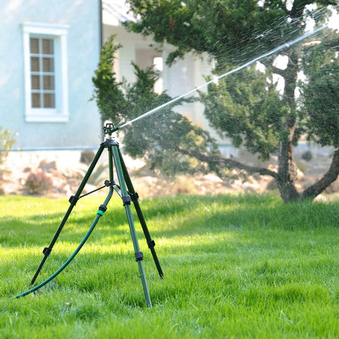 Heavy Duty Zinc Tripod Base Impact Sprinkler, 360 Degree Rotating, 3 Height Adjustable Steel Sprinkler Head, A Workhorse For Large Yards, Farms, And Garden Beds in operation on a lawn near a house, spraying water.