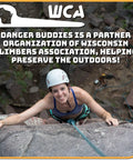 A climber wearing a helmet smiles while scaling a rock face, showcasing the adventure of outdoor climbing.