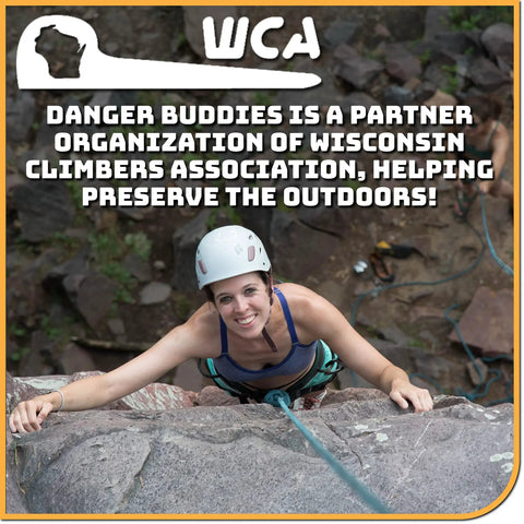 A climber wearing a helmet smiles while scaling a rock face, showcasing the adventure of outdoor climbing.