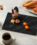 Natural Black Marble Cutting Board 12 By 8 Inch Real Stone Slab For Kitchen Counter And Cheese Board Elegant Marble Serving Tray For Appetizers Decor Or Barware Display with assorted appetizers on marble table.