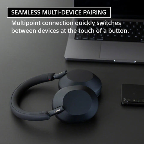 WH-1000XM5 Premium Noise Canceling Headphones with Auto NC Optimizer black on desk next to laptop showing multi-point pairing