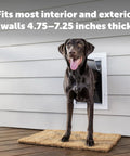 Heavy Duty Wall Entry Dog Door With Telescoping Frame Built Damn Tough Rust Proof Plastic Construction Zero Draft Insulation Slick Slide Flap No Fuss Install For Medium Dogs with a dog at the entrance.
