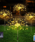 Solar Powered Firework Garden Lights 4 Pack With 120 LED Starburst String 8 Modes Remote Control Flexible Copper Wire Outdoor Fairy Lights illuminating a lawn.