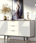 Modern white and gold cabinet with abstract wall art and decorative vase in elegant living room setting.