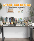 Solid Electric Adjustable Standing Desk With 40x24 Inch Tabletop, folding corner office table, set up with books and stationery.