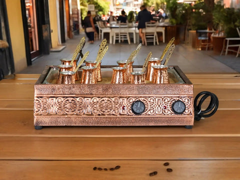 Authentic Turkish Copper Electric Hot Sand Coffee Maker Heater For Ottoman Style Use 110V 220V Dual Voltage Includes Ten Turkish Coffee Pots Durable Copper Finish Makes It A Showpiece For Your Kitchen And Cafe on a table in an outdoor setting