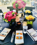 Restaurant table setting with Mexican Tile Mix 100 Tiles 4x4 Ceramic Squares as napkin holders, surrounded by floral centerpieces.