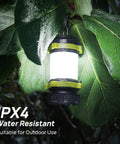 Rechargeable LED Camping Lantern With USB C Power Bank, 6 Lighting Modes hanging in wet leaves, IPX4 water resistant feature shown